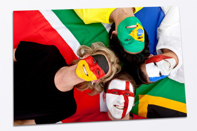 Vier Menschen die auf dem Rücken liegen, mit den Köpfen zusammen und jedes Gesicht ist mit einer anderen Flagge geschminkt.