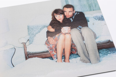 Postkarte mit Salz-Effekt. Ein junges Pärchen sitzt auf einem eingeschneiten Sofa