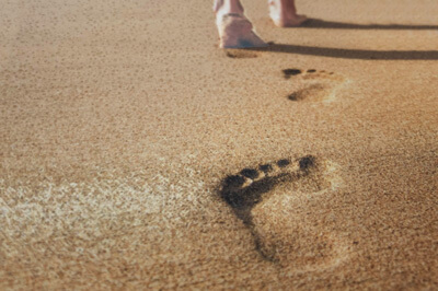 Postkarte mit Sand, Füßen und Fußabdrücken